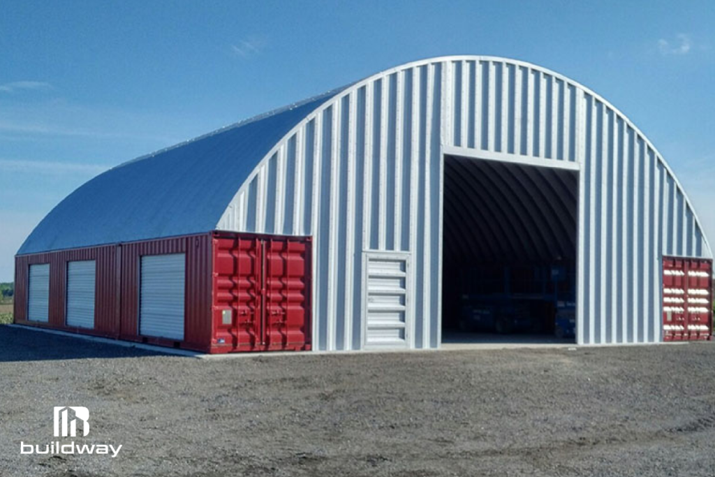 Large arched steel structure built on red shipping containers, offering durable and spacious residential storage or workshop space by Buildway.