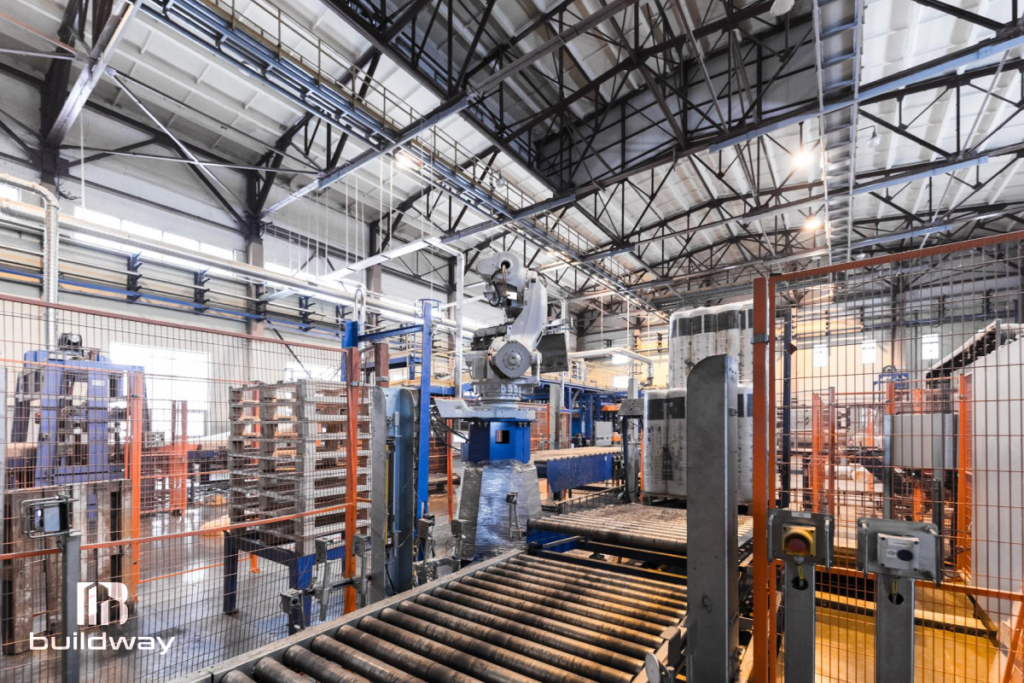 Interior view of an industrial manufacturing plant with automated machinery, conveyor systems, and steel framework designed by Buildway.