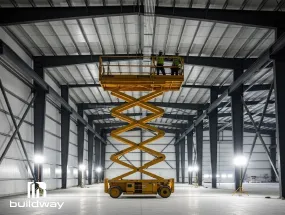Workers installing insulation inside a large CFS building using a yellow scissor lift, highlighting Buildway’s energy-efficient design.