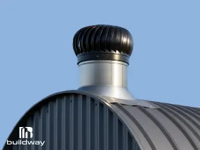 Black and silver turbine vent installed on the curved roof of a Quonset building by Buildway, designed for efficient airflow and ventilation against a clear blue sky.